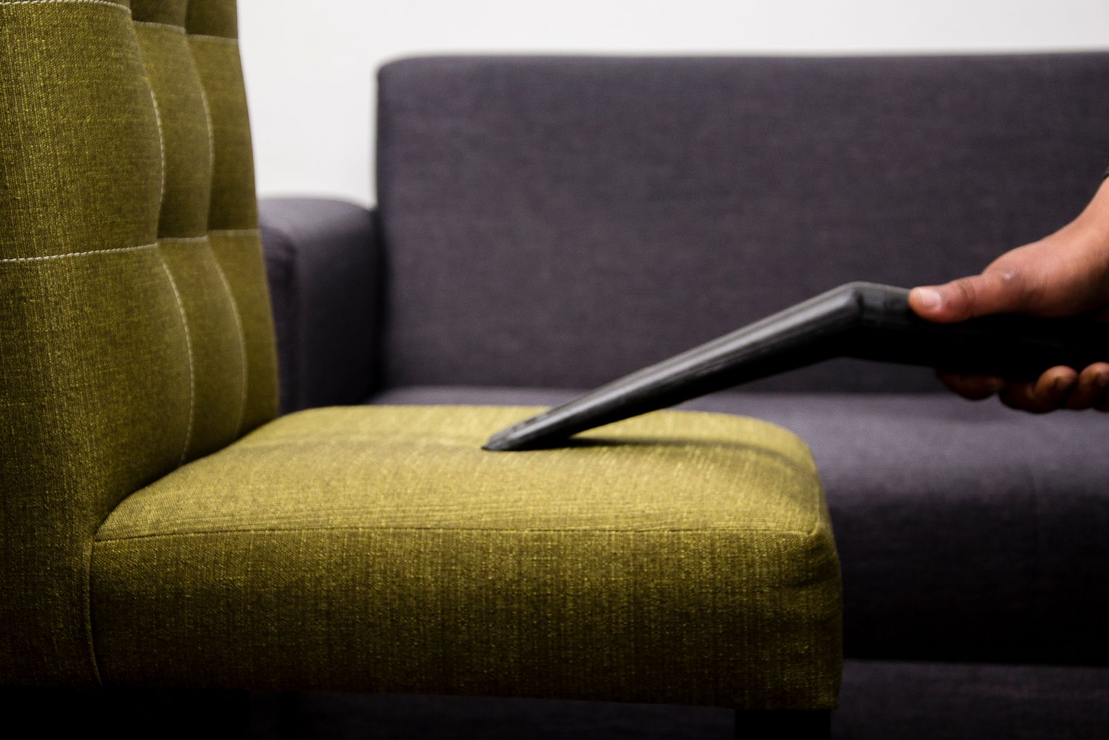 A portable upholstery cleaner lifting a stain out of a fabric sofa cushion